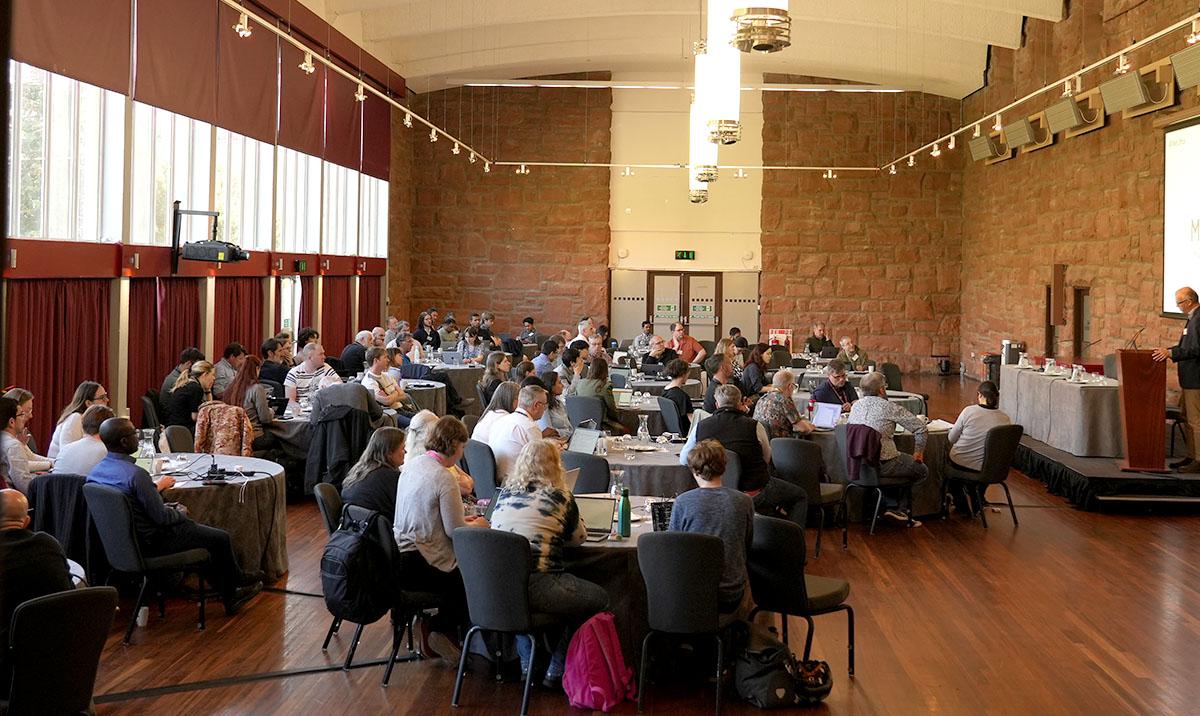 Photo shows seated audience listening to speaker