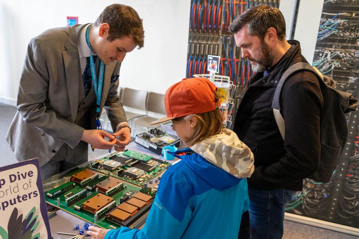 2 men and one boy at a table with computer hardware