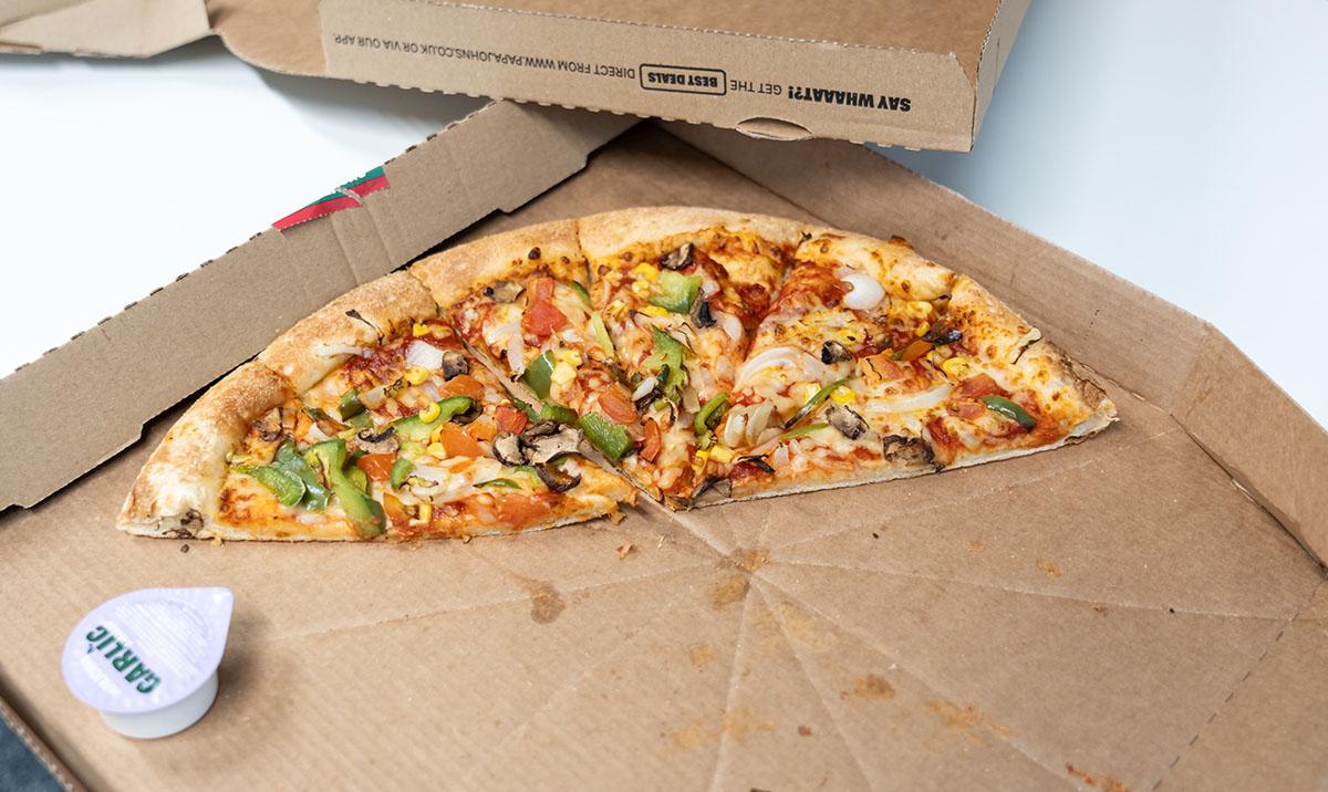 Slice of pizza in takeaway box.