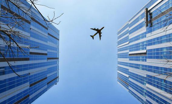Photo shows aircraft above high-rise buildings. 