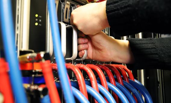 Close-up photo shows the hands of ACF staff member working with ARCHER2 hardware