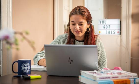 Woman looking at laptop in study space setting.