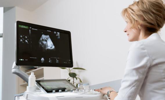 Medical setting. Woman looks at ultrasound image on screen.